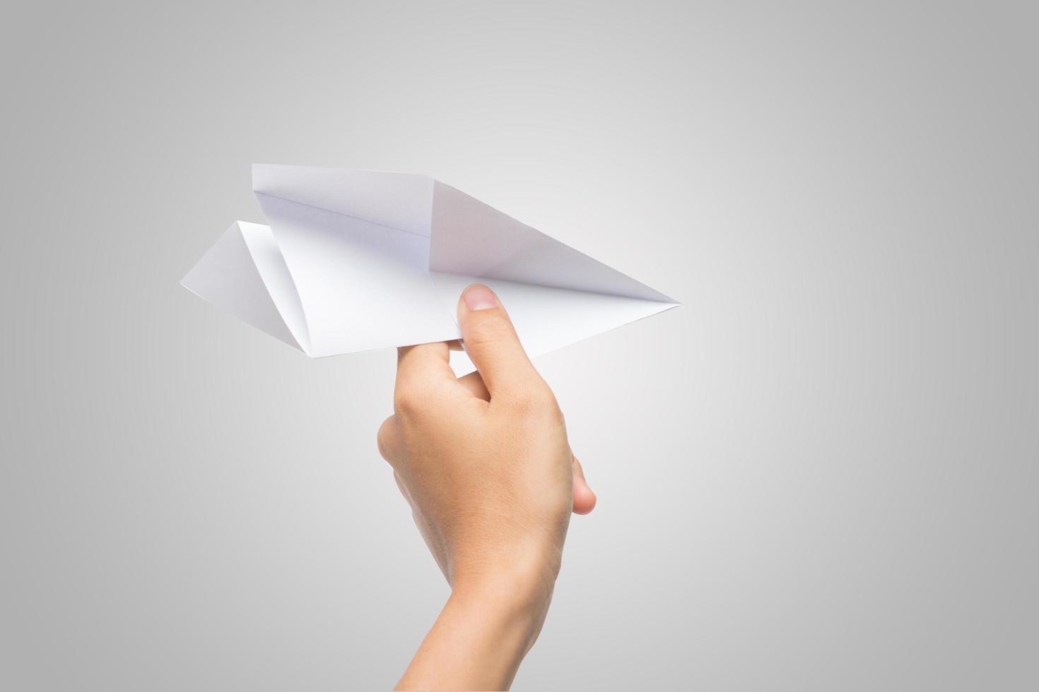 La mano de una mujer sostiene un avión de papel sobre fondo blanco. foto