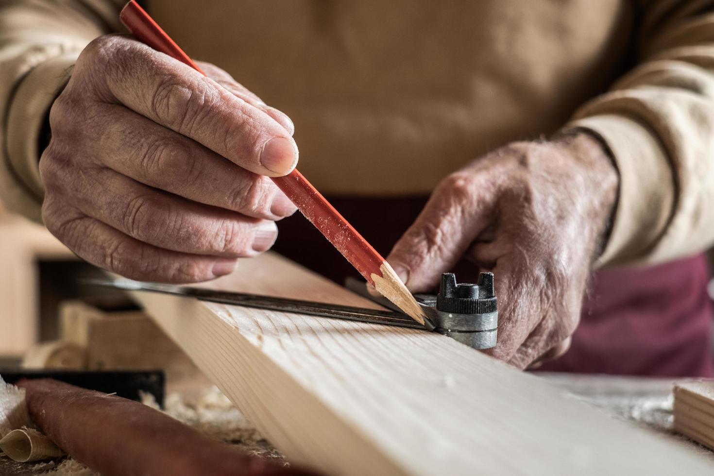 carpintero midiendo una tabla con un lápiz rojo y una regla de metal foto