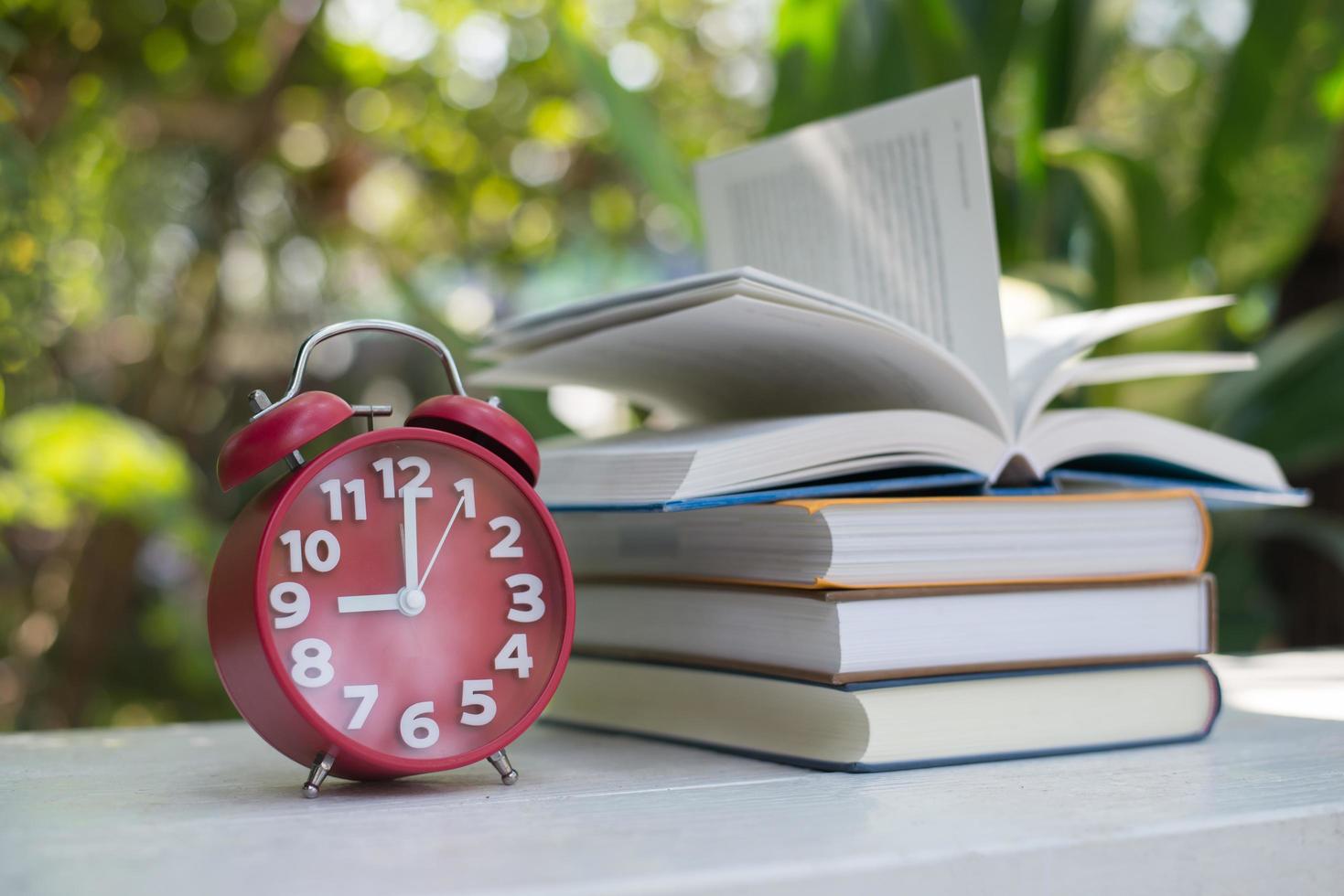 Red alarm clock with book on nature garden background photo