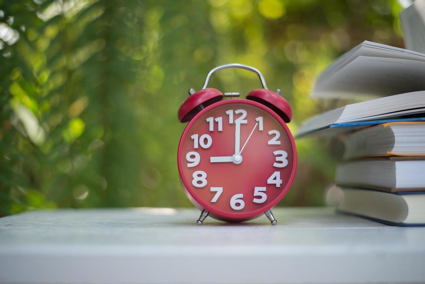 Red alarm clock with book on nature garden background photo