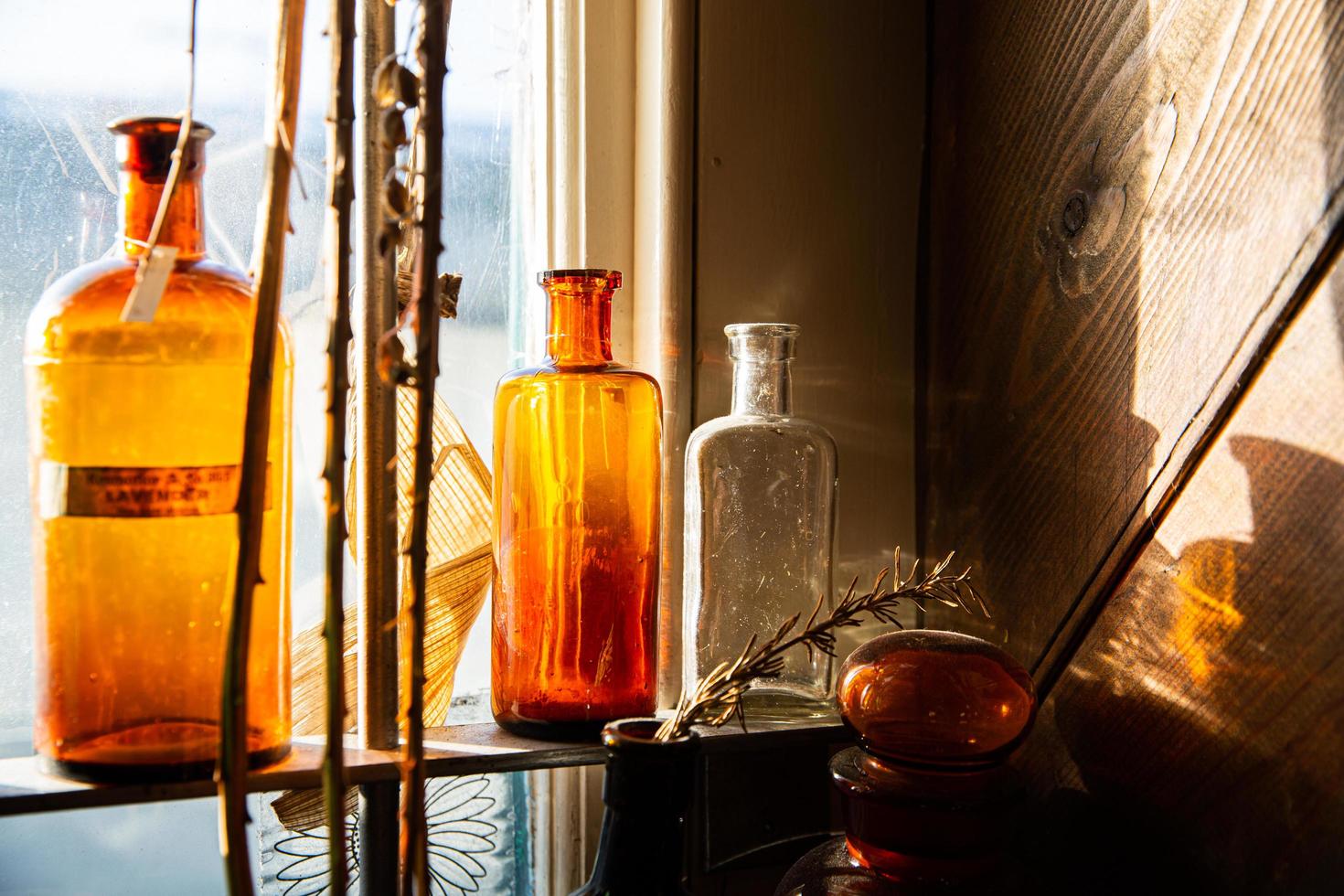 Glass bottles on a shelf near a window photo