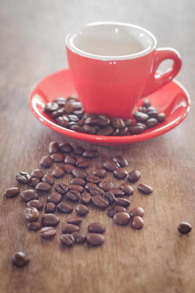 Red coffee cup with coffee beans on a wooden table photo