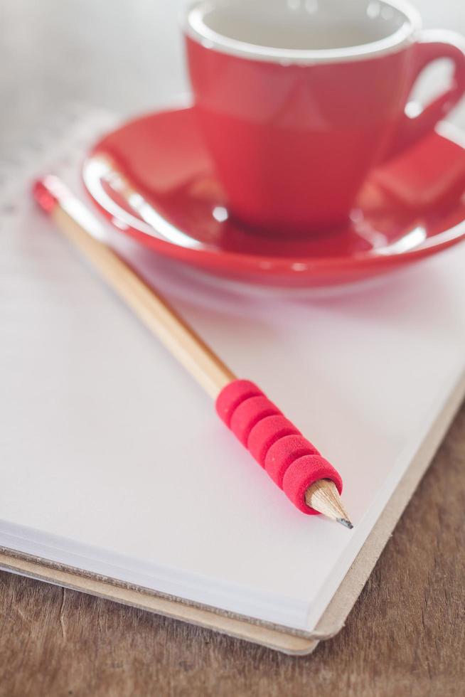 Red mug and a notebook and pencil photo