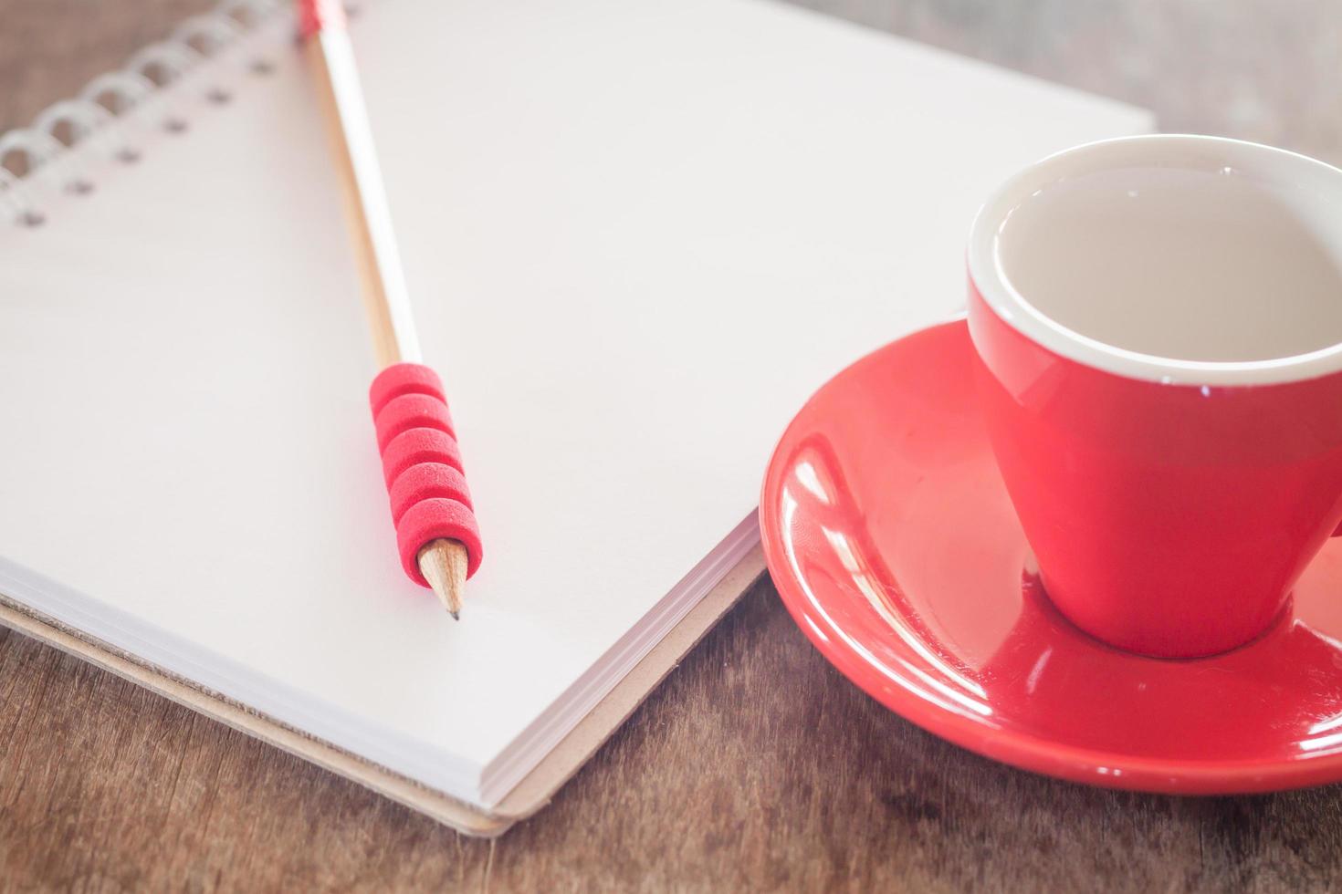 taza roja con lápiz y cuaderno foto