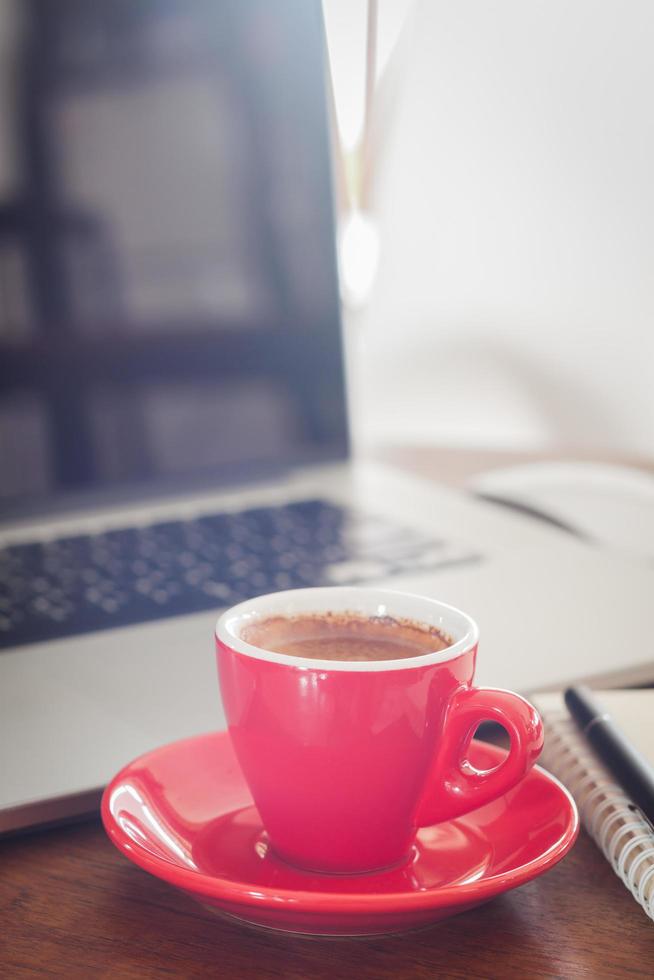 taza de café roja y laptop foto