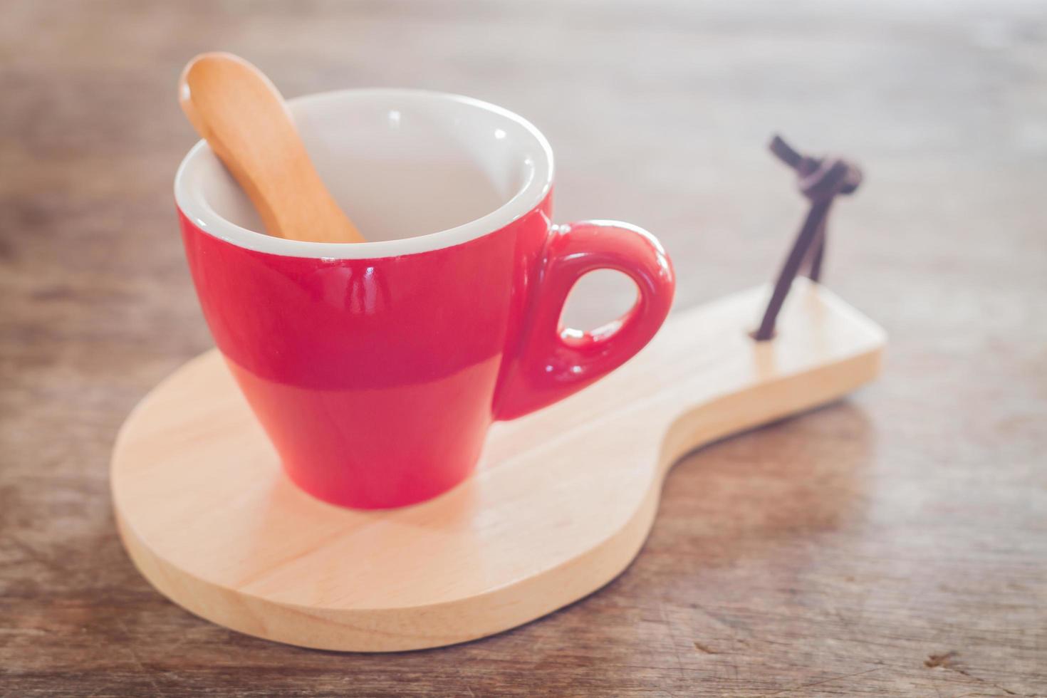 taza roja con una galleta y una bandeja de madera foto