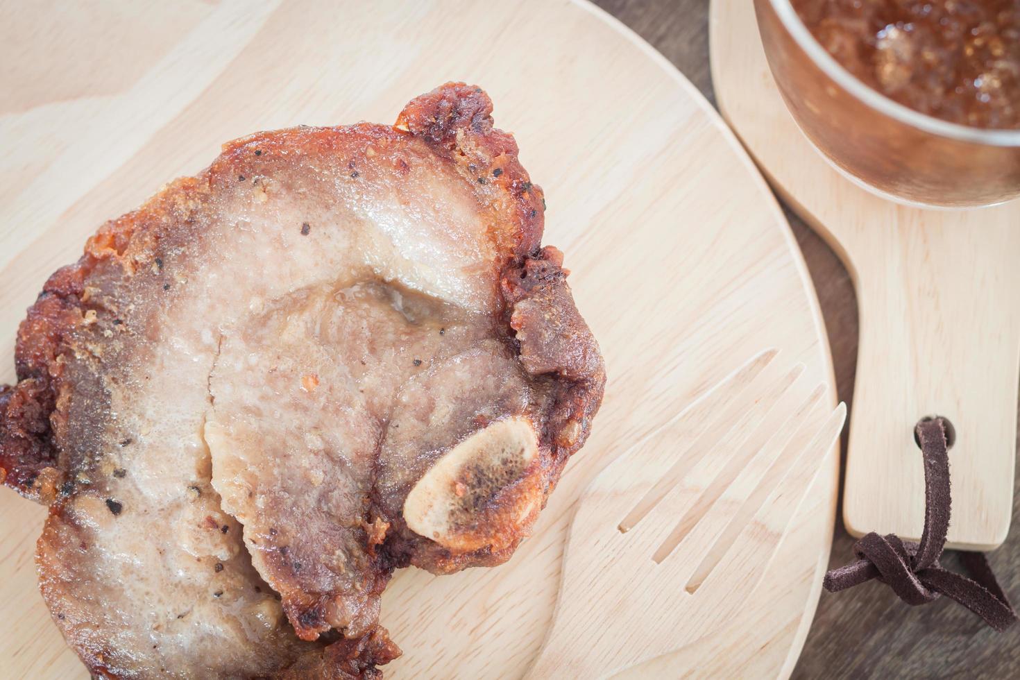 Close-up of pork steak on a wooden plate photo