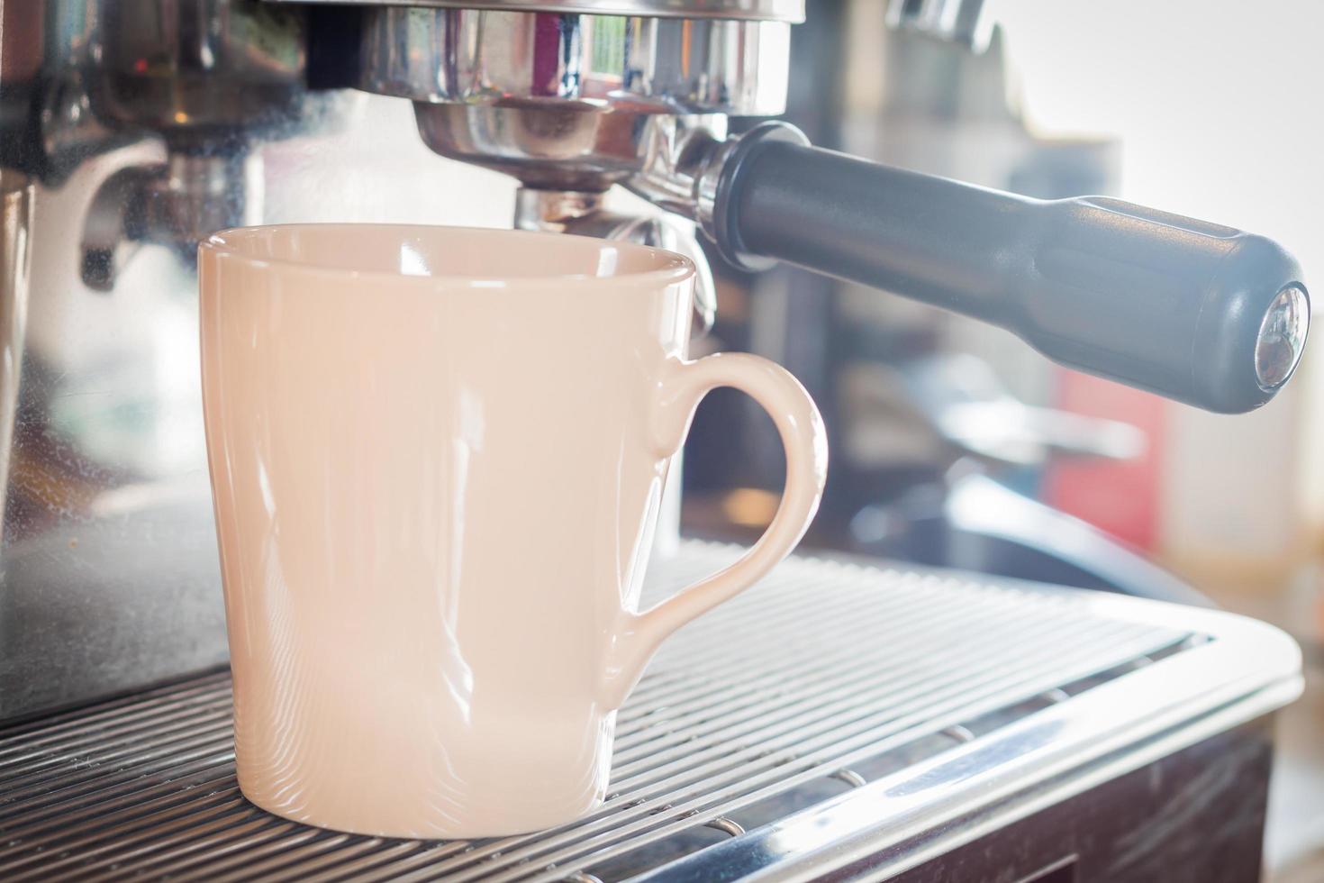 taza de café debajo de una máquina de café espresso foto