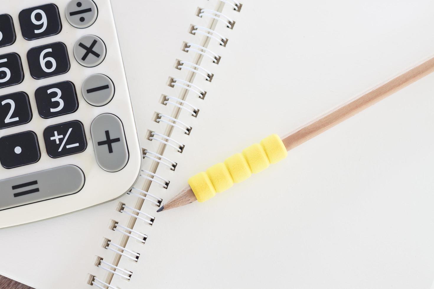 Open notebook with a yellow pencil and calculator photo