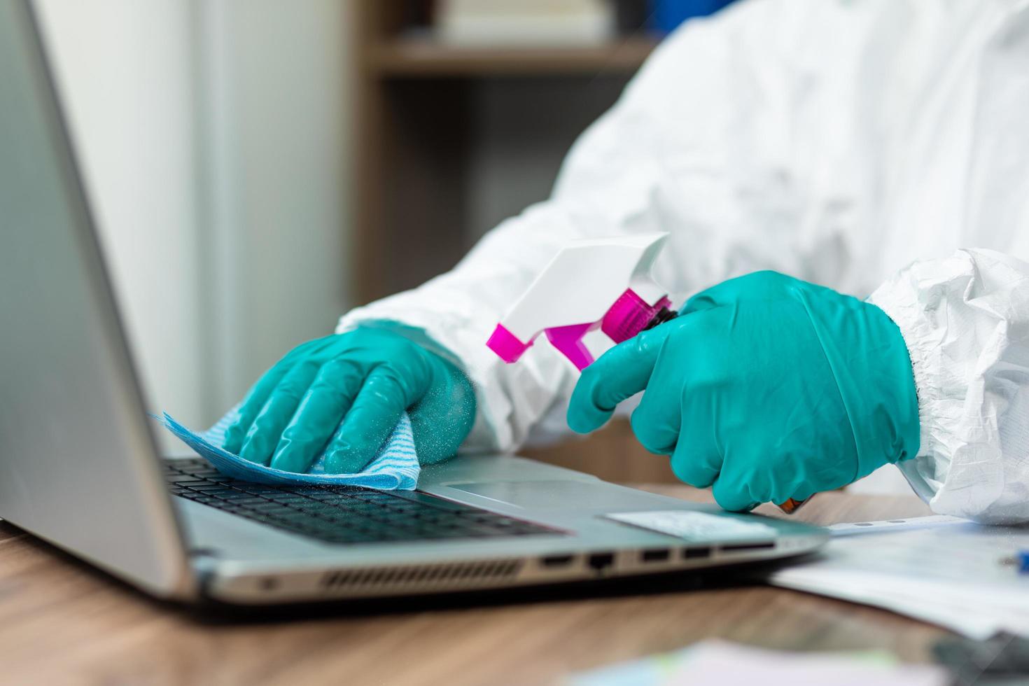 Person in protective suit cleaning a notebook keyboard photo
