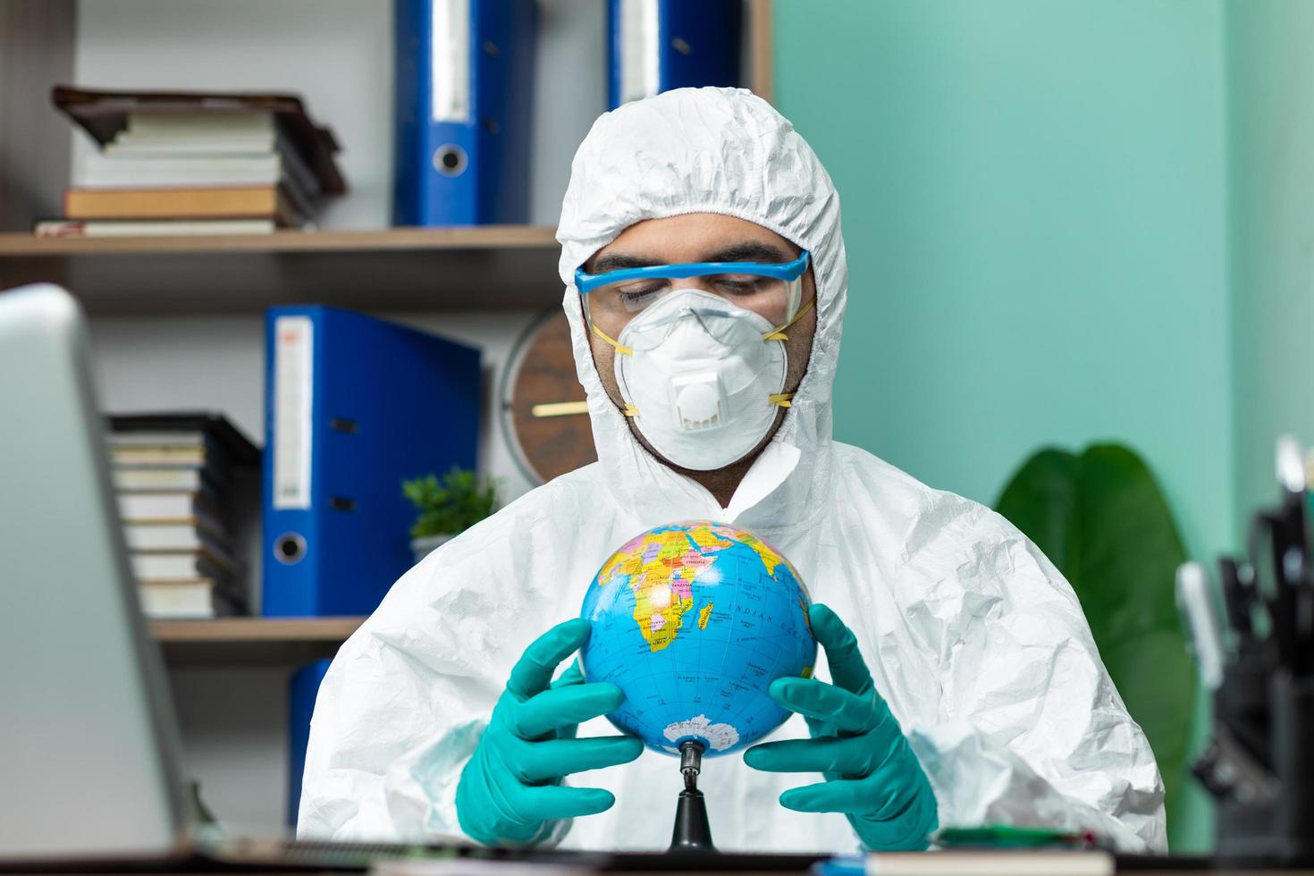 Person in protective suit holding globe earth with hand at office photo