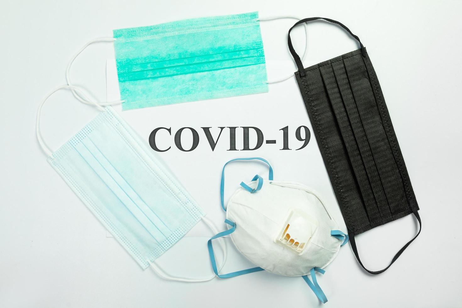 Medical protective masks on the table with COVID-19 word photo