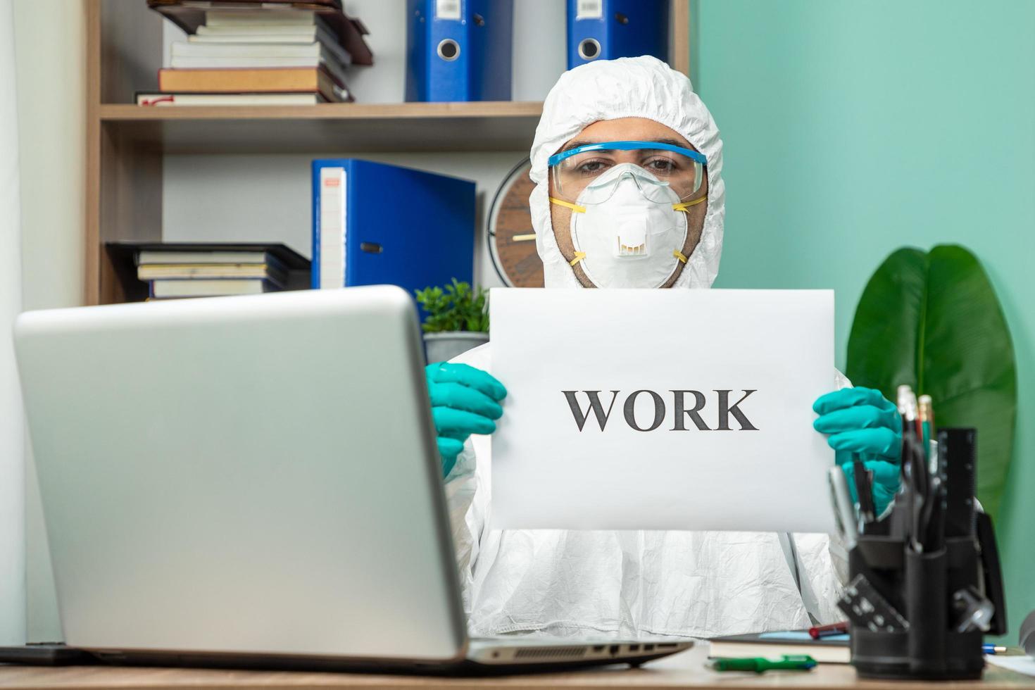 Person in protective suit holding work word at office photo