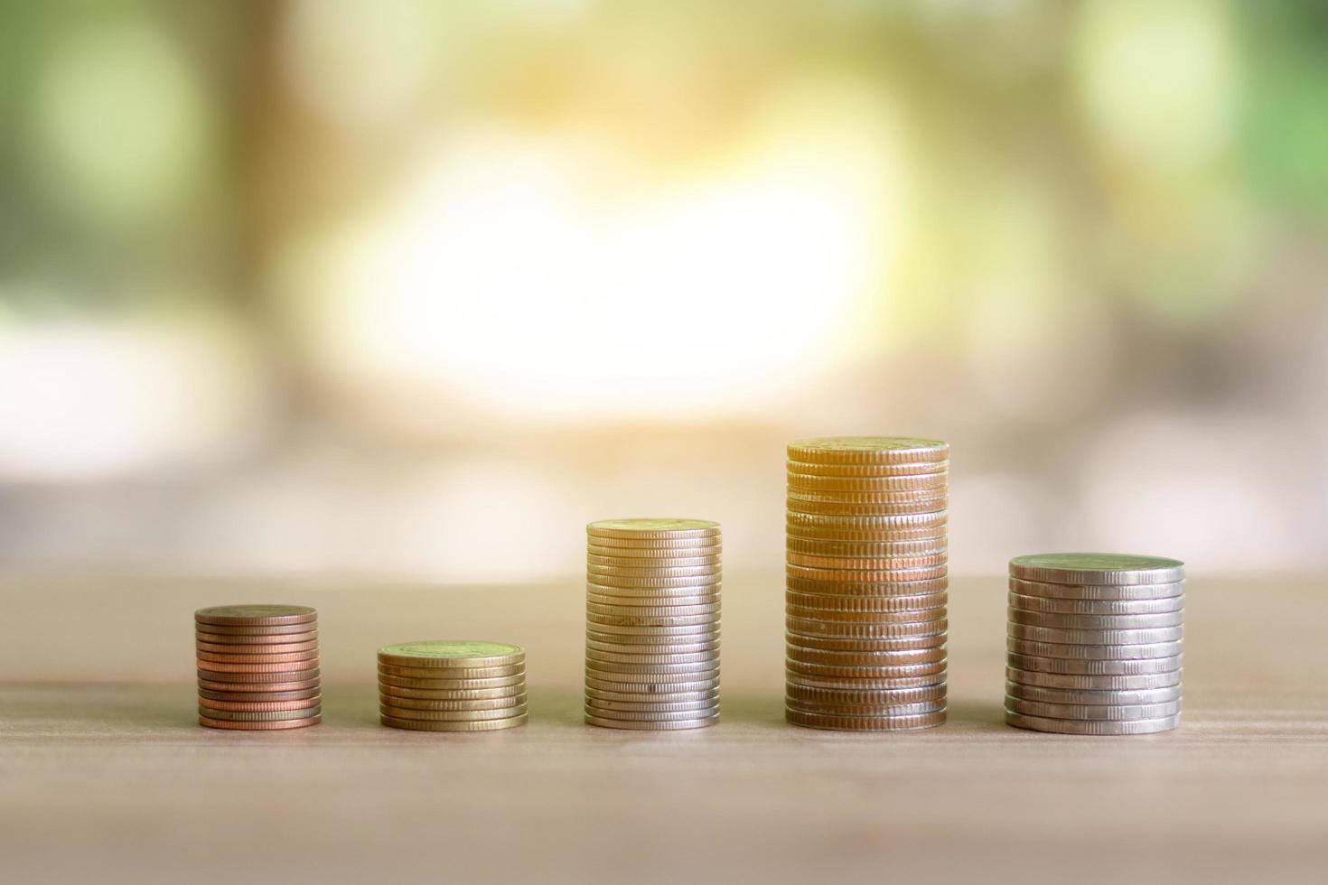 Stack of coins on wood table with bokeh background photo