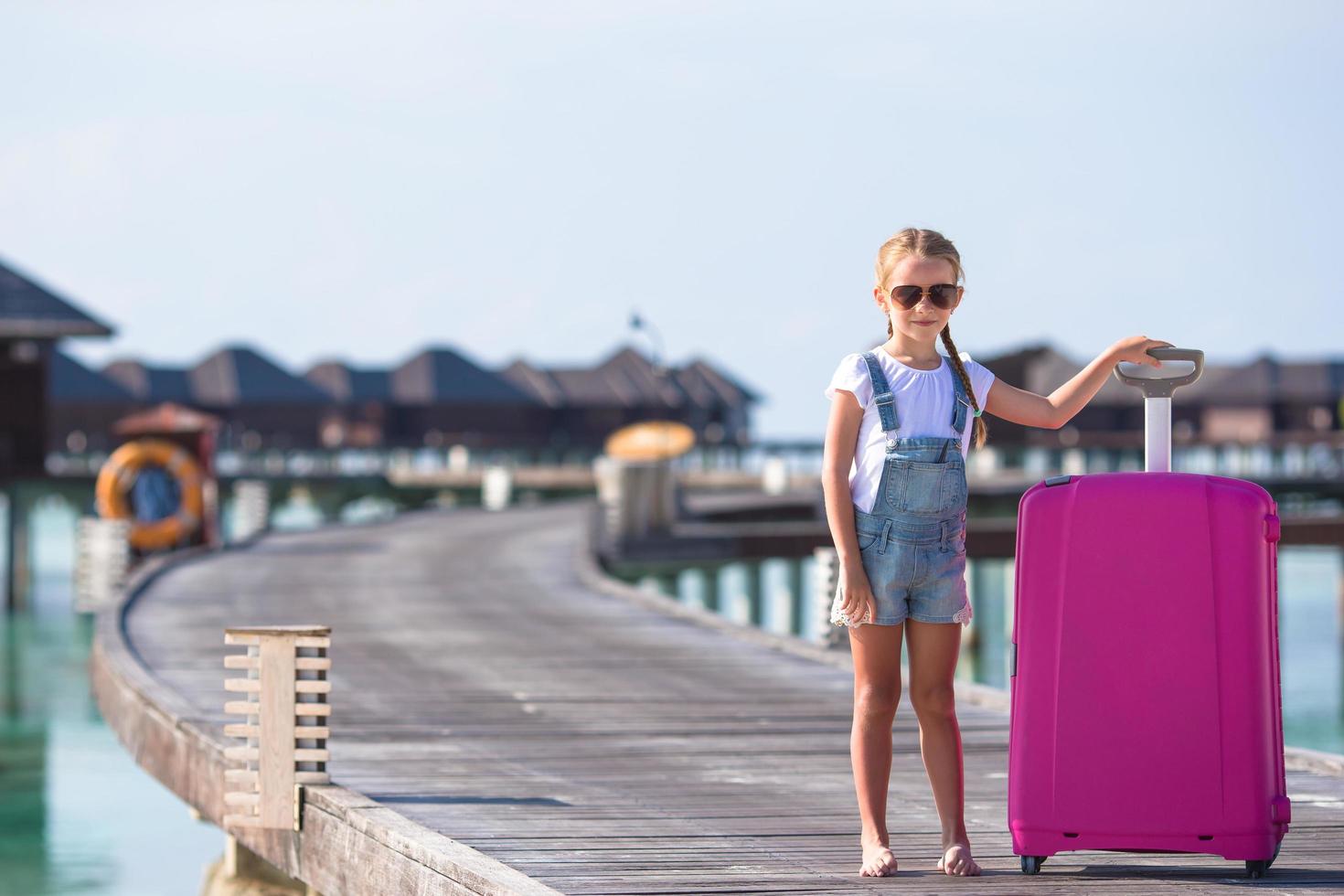 Maldives, South Asia, 2020 - Girl with luggage on a dock at a resort photo