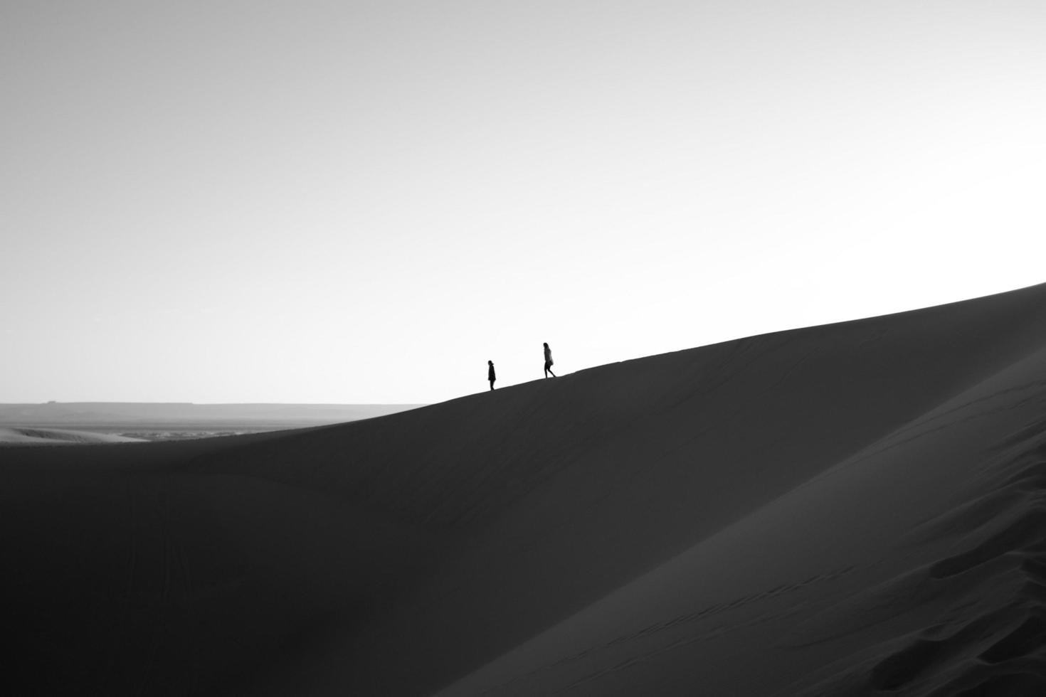 Silhouette of two people walking on desert ridge photo