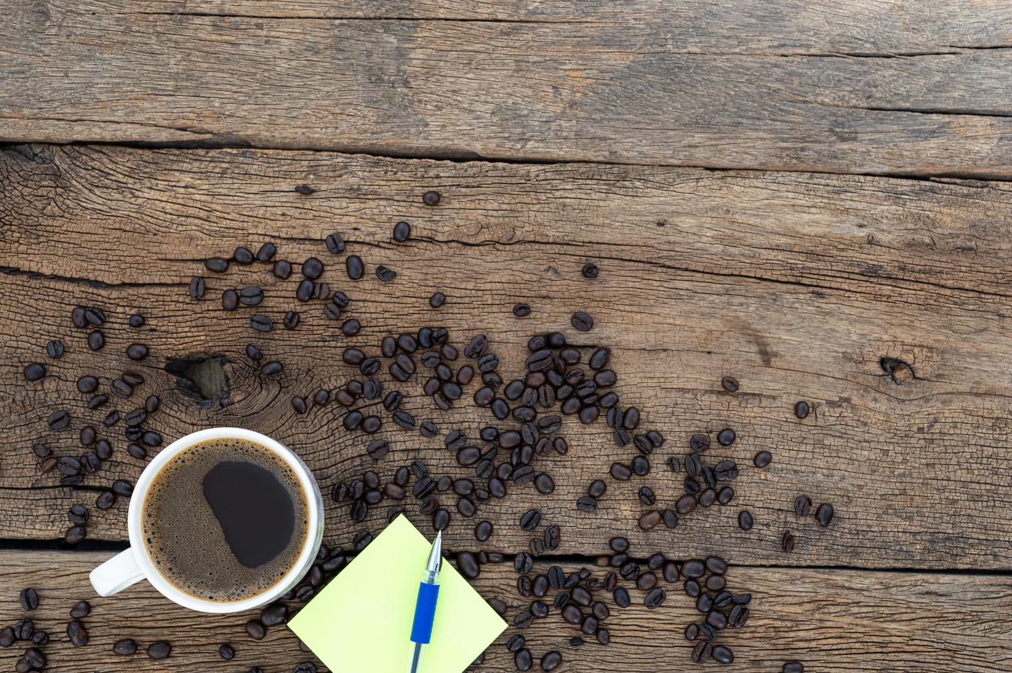 Note pad and coffee on wooden table, top view photo