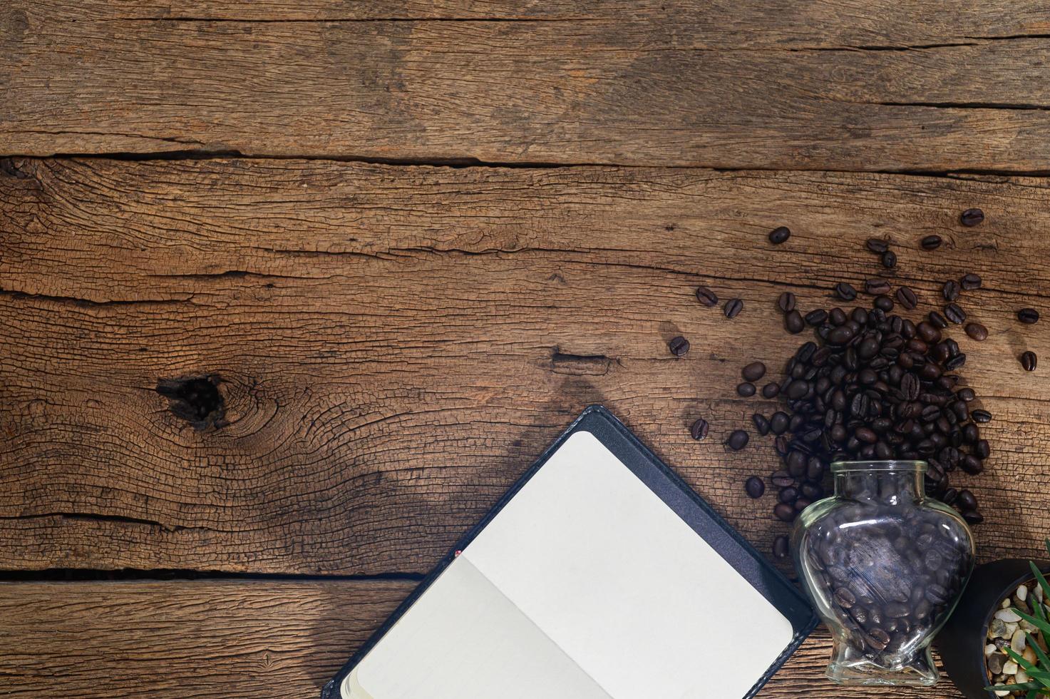 escritorio de madera con granos de café y cuaderno foto