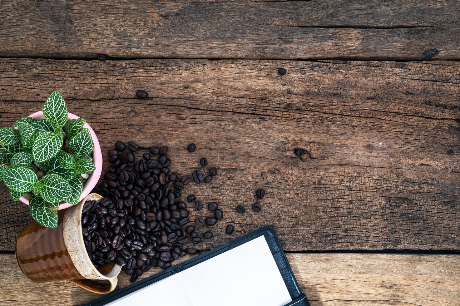 escritorio de madera con cuaderno y granos de café foto