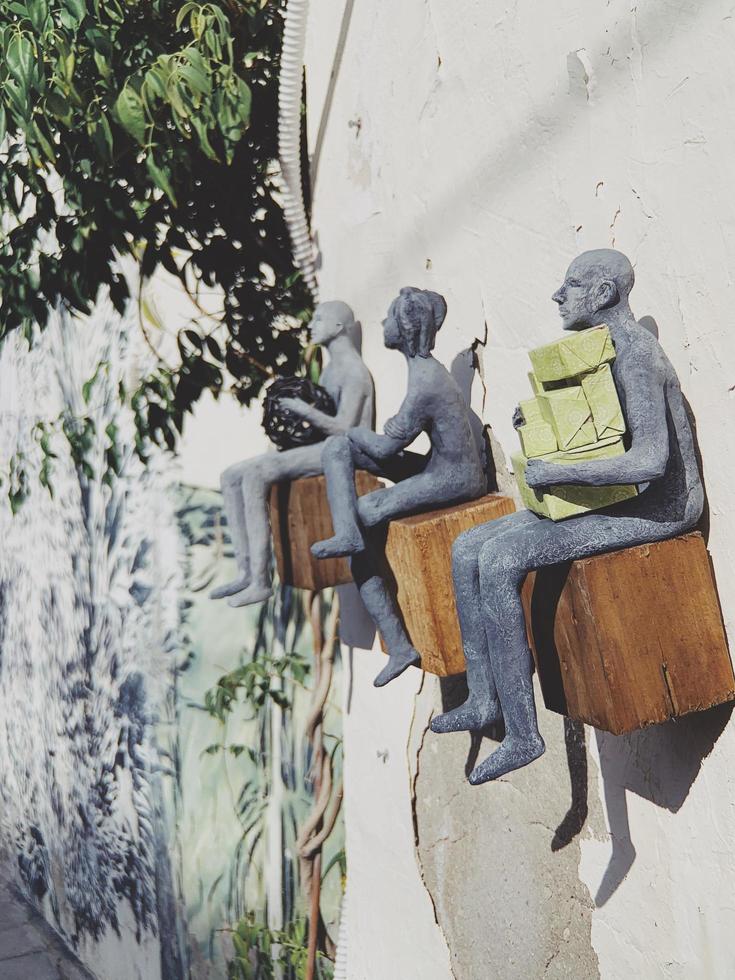 Tel Aviv-Yafo, Israel, 2020 - Three statues sitting on wooden blocks photo