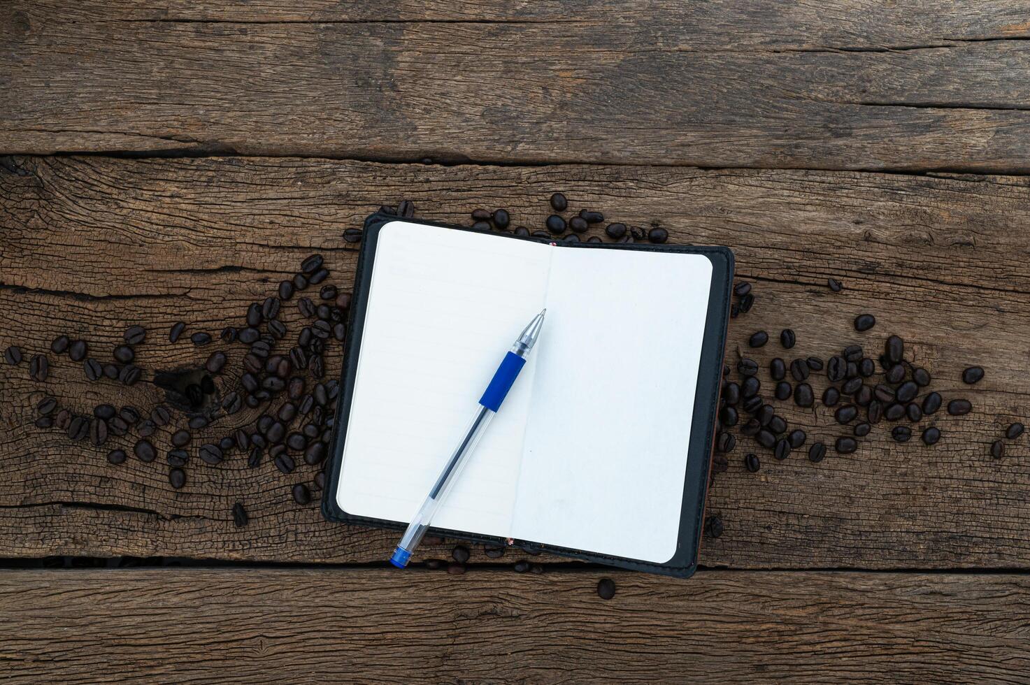 Wooden desk with notebook and coffee beans photo