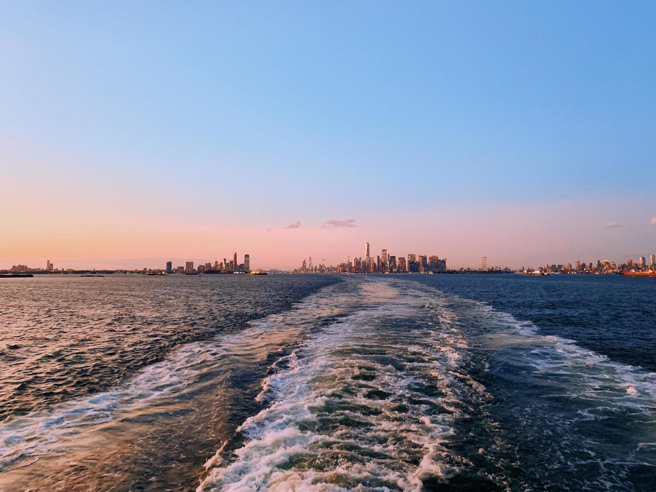 Body of water with a city in the distance at sunset photo