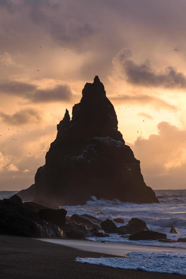 silueta de una roca en el mar durante la puesta de sol foto