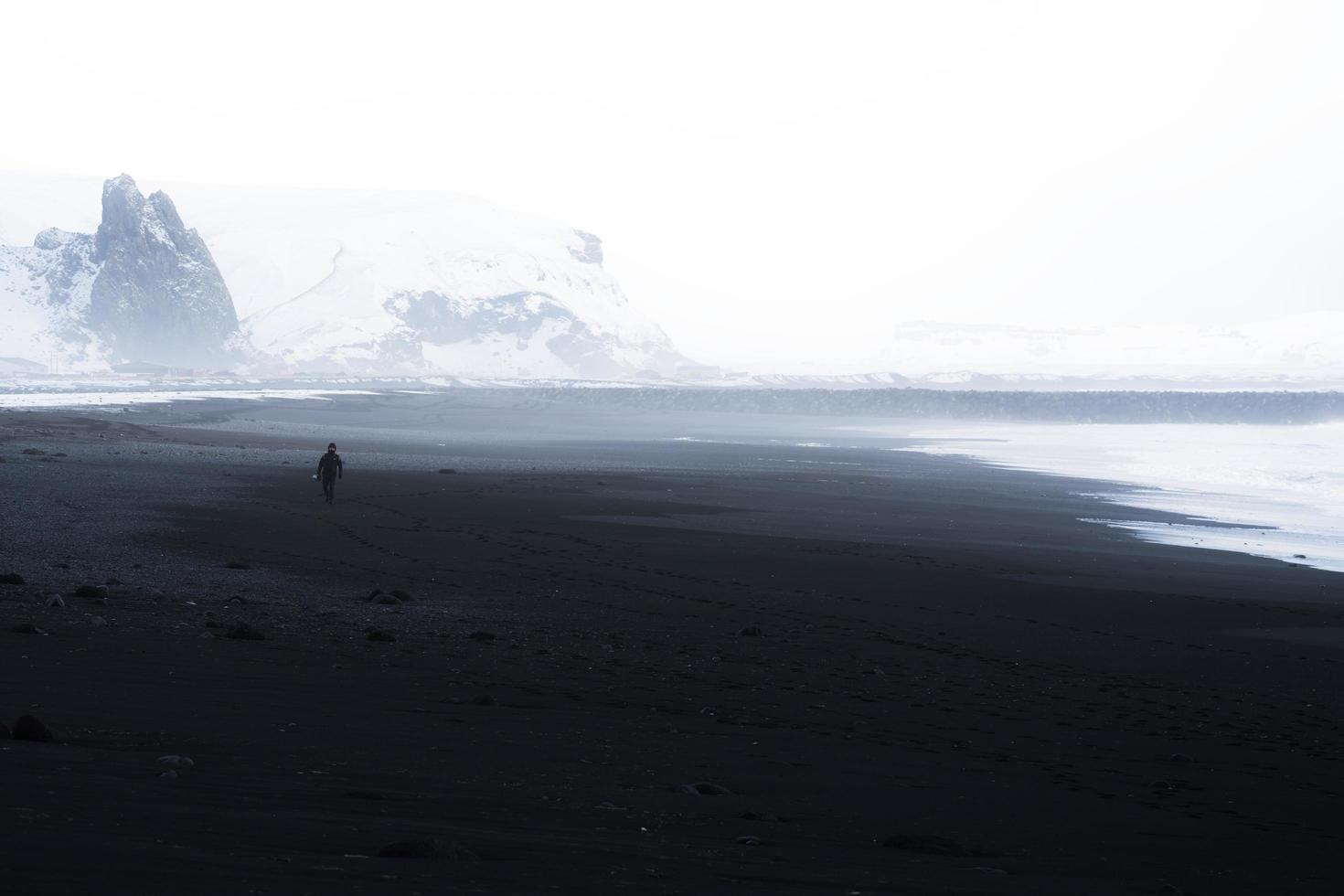Black and white of a person walking on a beach photo