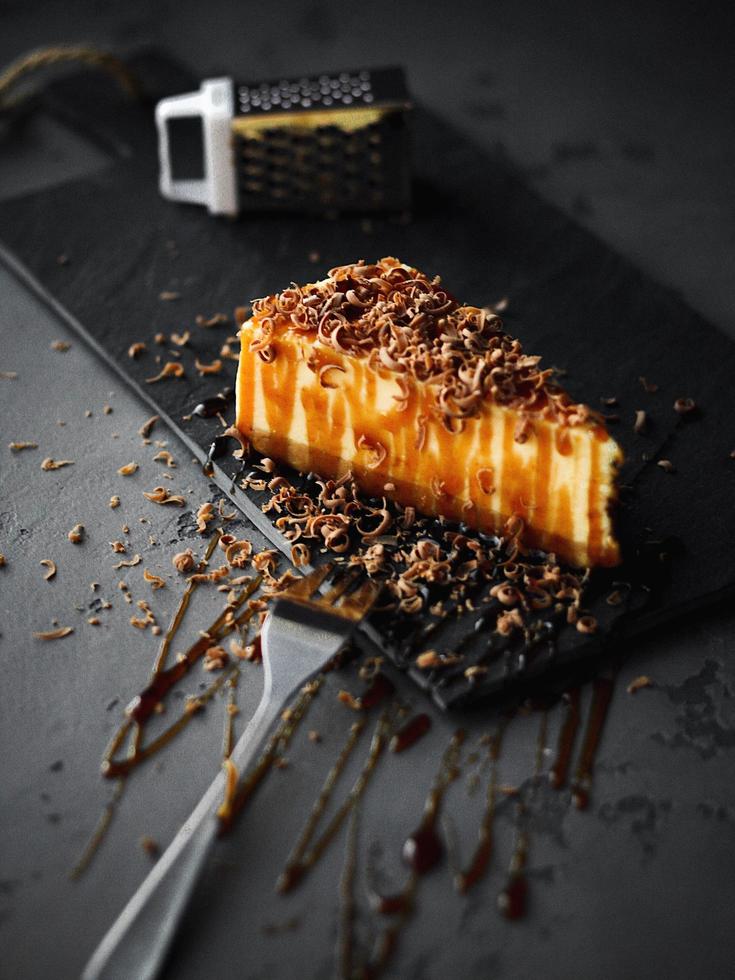 Rebanada de tarta de queso con caramelo en una placa negra foto