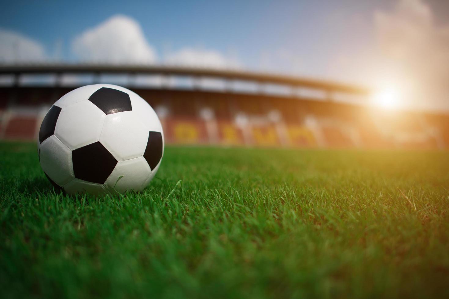 Soccer ball on grass with stadium background photo