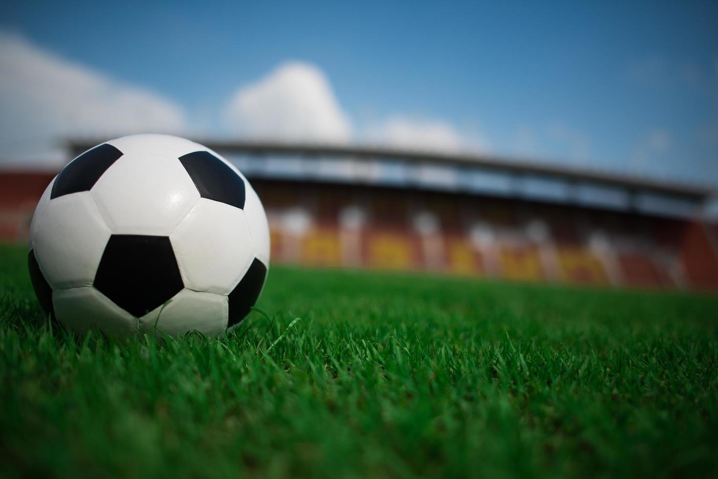 A soccer ball on grass with stadium background photo