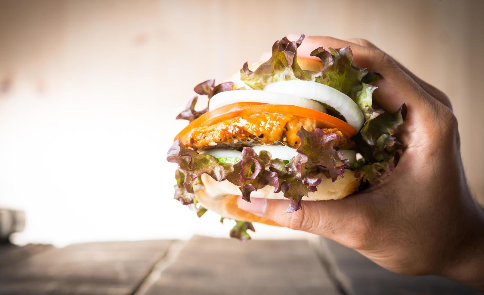 Hands hold burger over cutting board photo