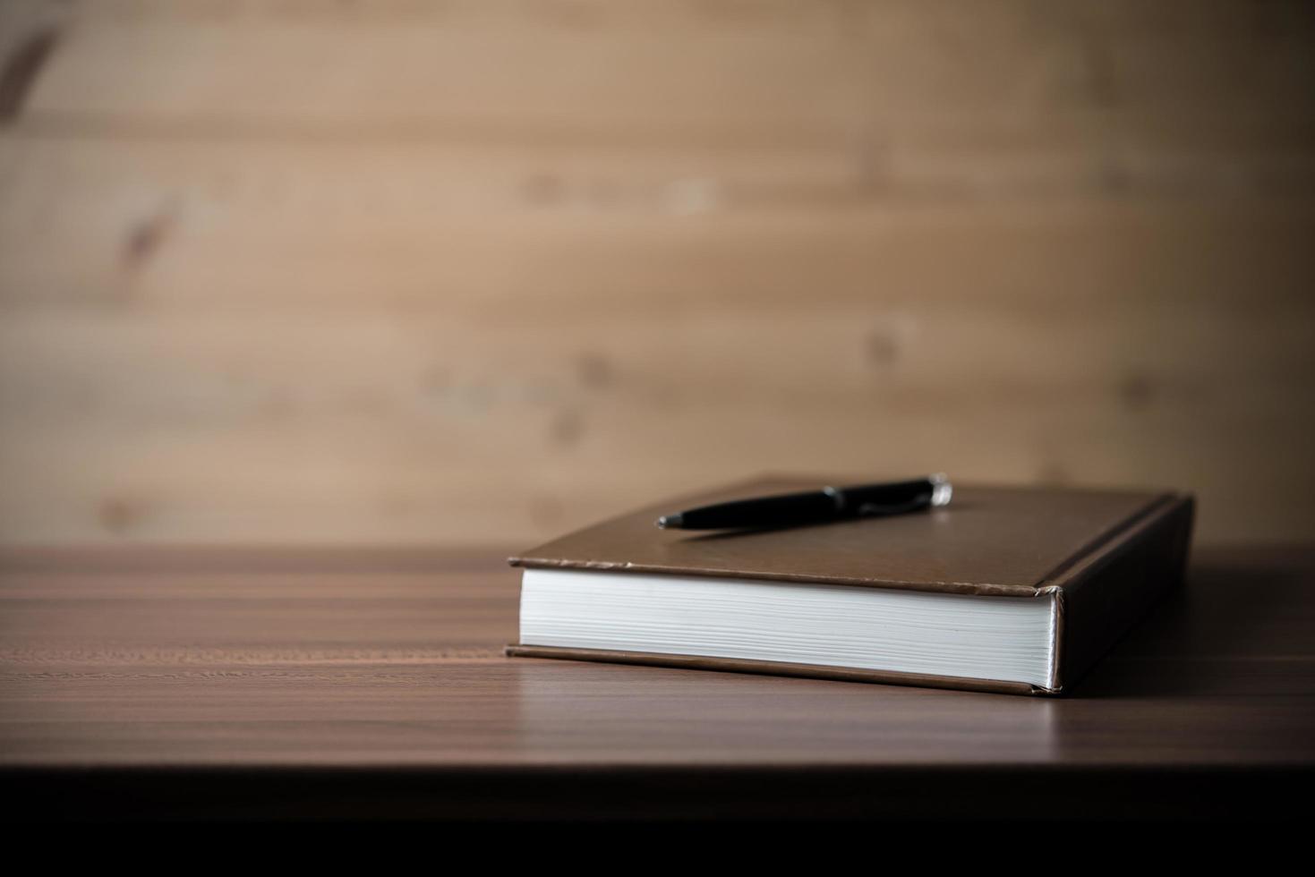 Book with a pen on wooden table photo