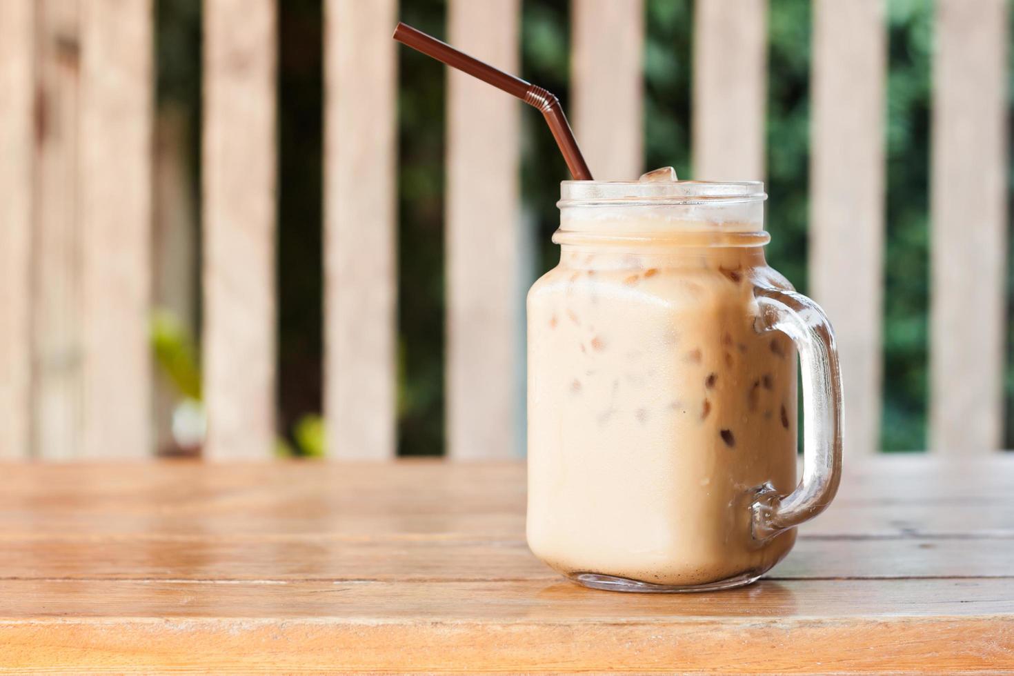 Vaso de café helado en una mesa de madera en el exterior foto