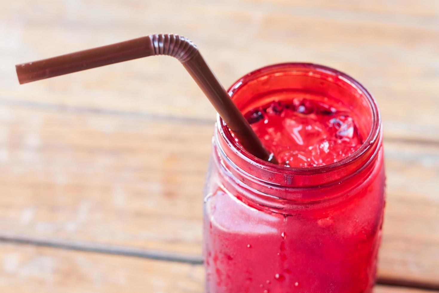 Iced drink in red glass jar with a straw photo