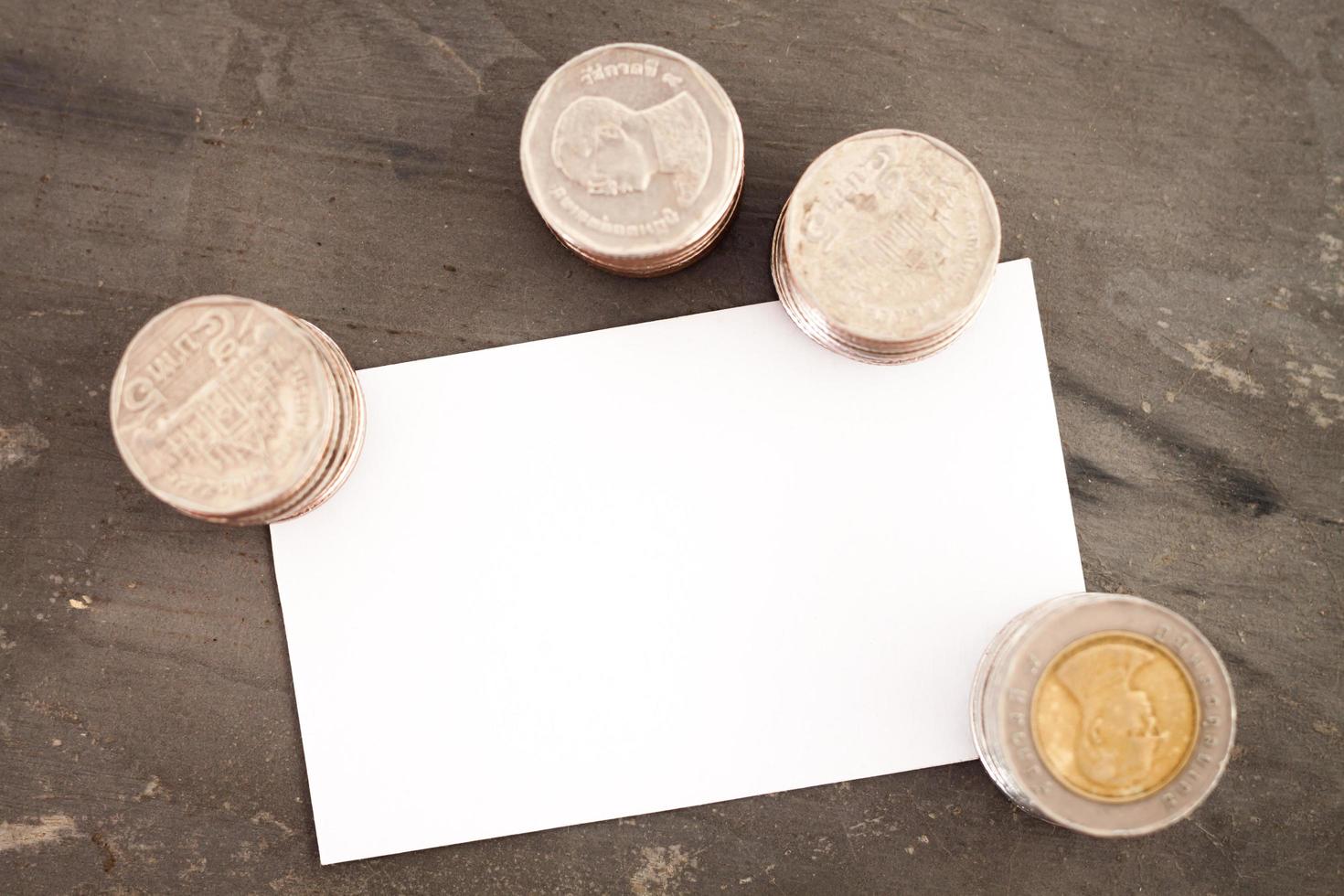 Tarjeta de nombre en blanco con monedas sobre una mesa foto