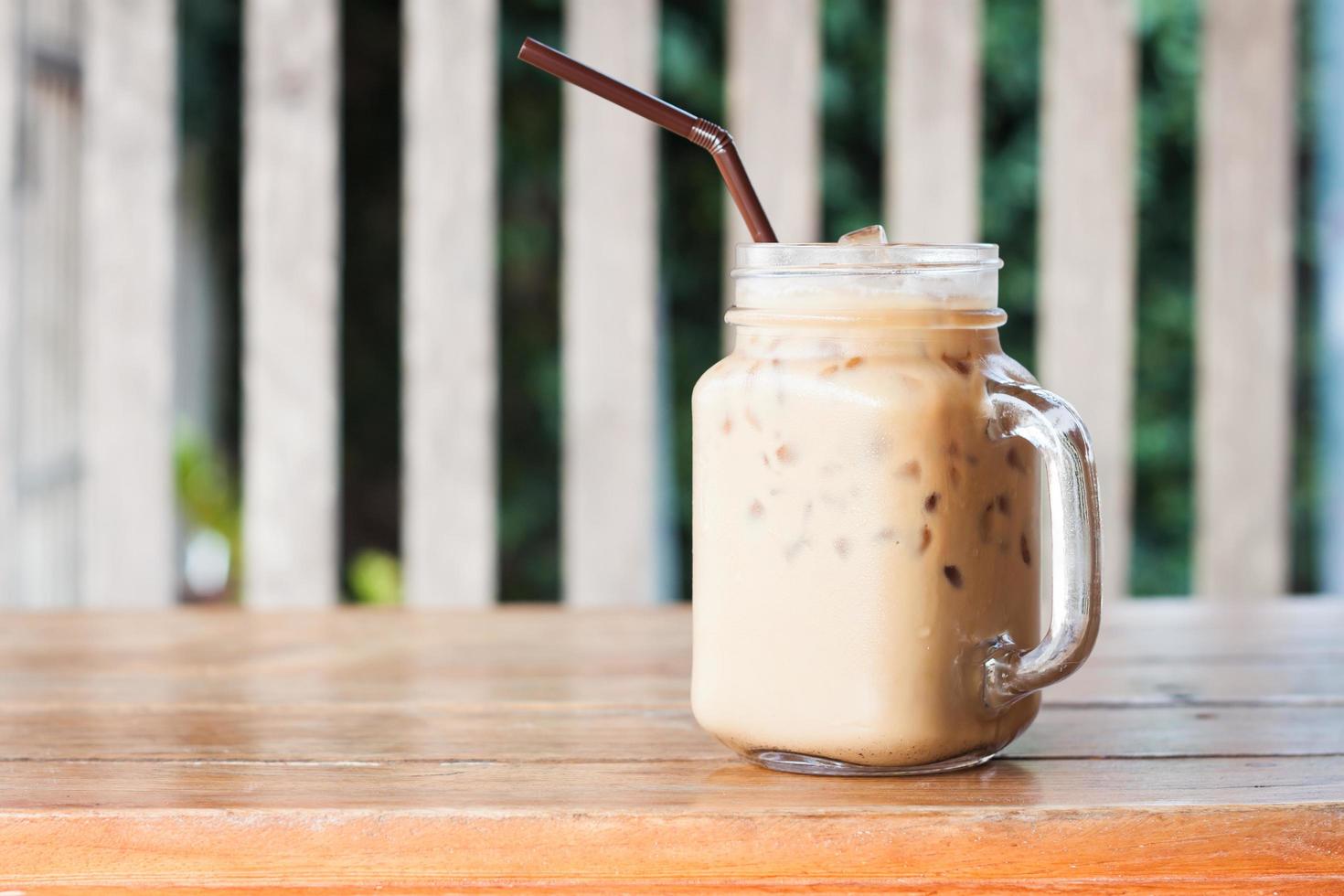 Glass of iced coffee on a wooden table at a cafe photo