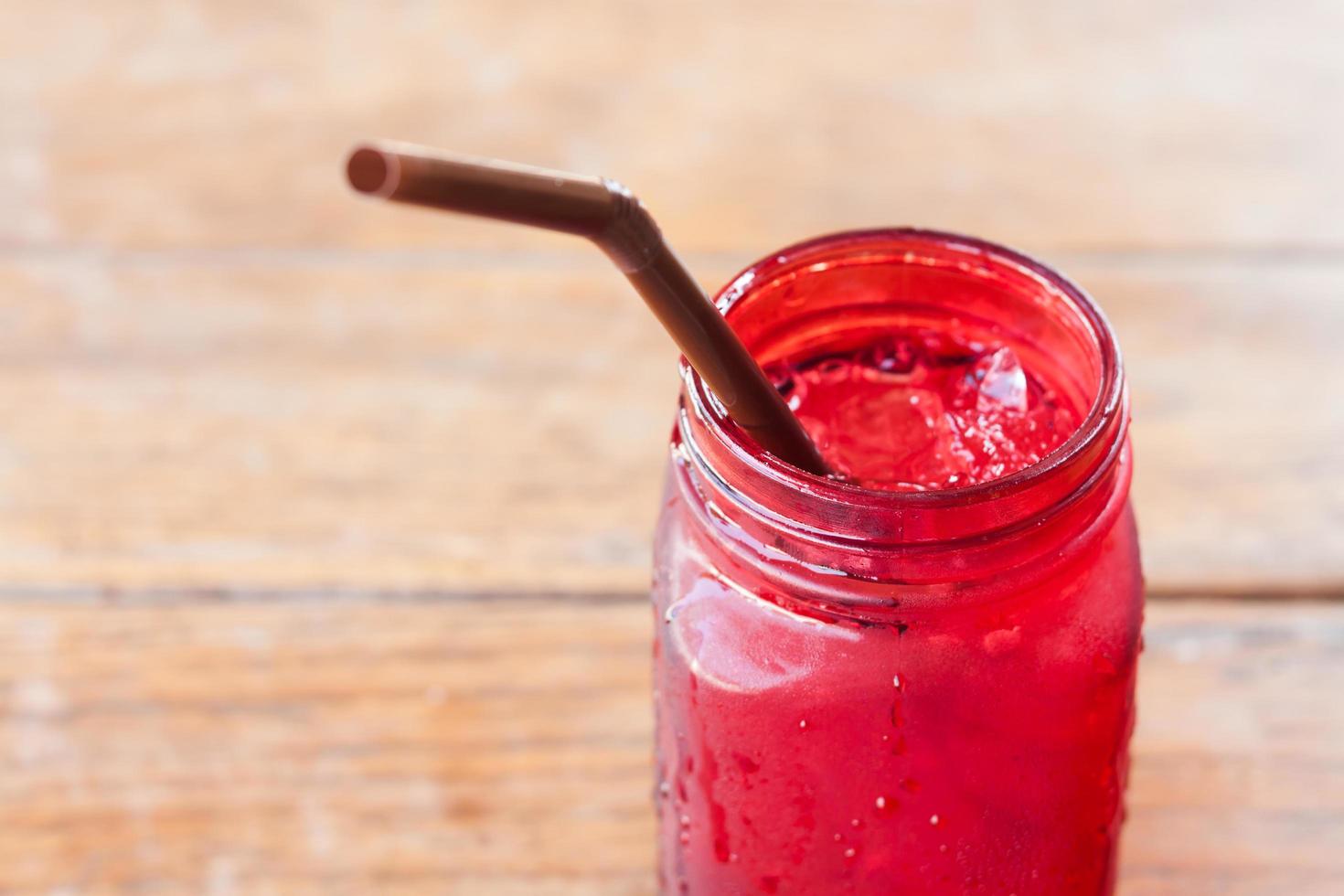 Close-up of an iced drink in red glass on a wooden table photo