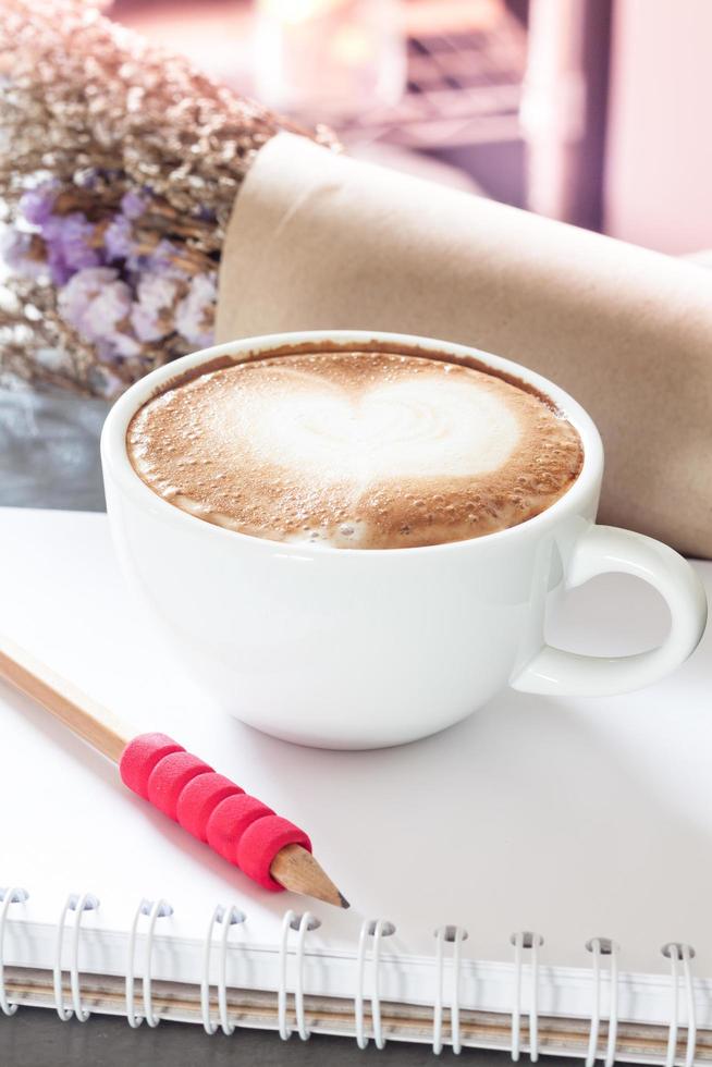 Latte and pencil on a notebook with flowers photo