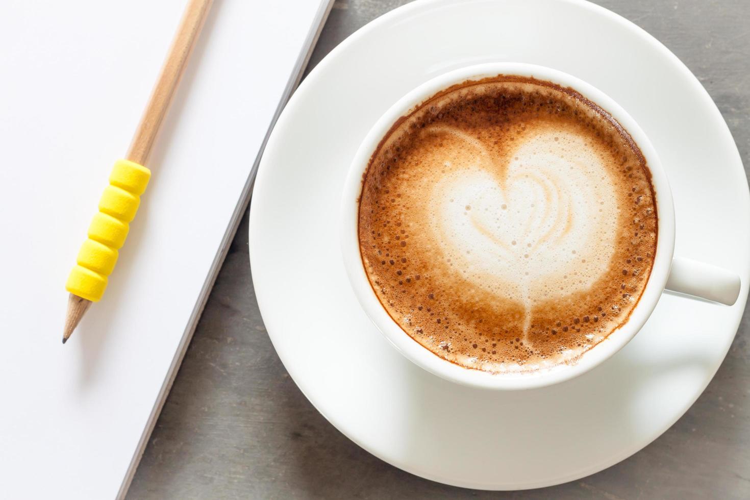 Taza de café con un bloc de notas sobre un fondo gris foto