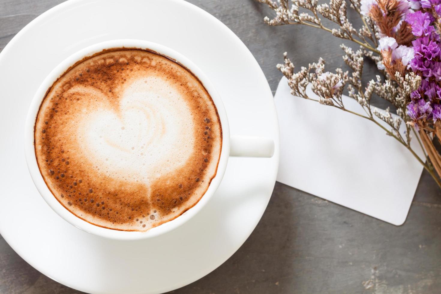 Vista superior de un café con leche y tarjeta de presentación con flores. foto