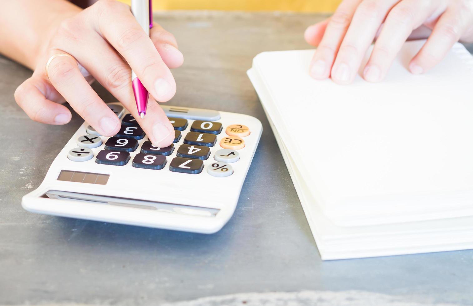 manos sosteniendo un bolígrafo y presionando los botones de la calculadora foto