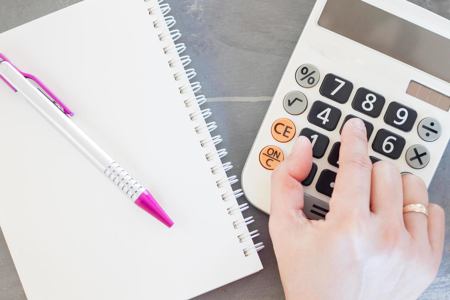 Hand on a calculator with a notepad photo