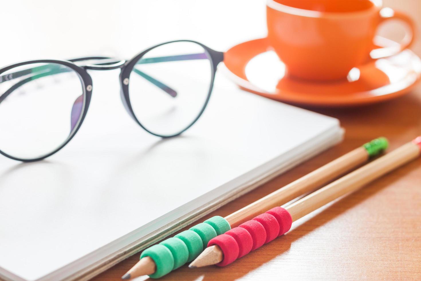 Pencils with glasses on a notebook with a coffee cup photo