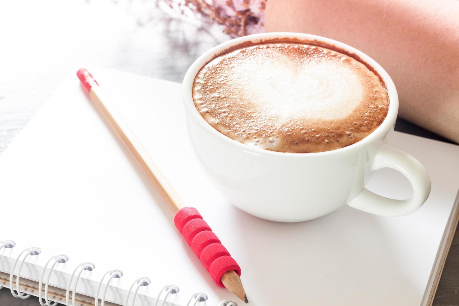 Latte with a pencil on a notebook photo