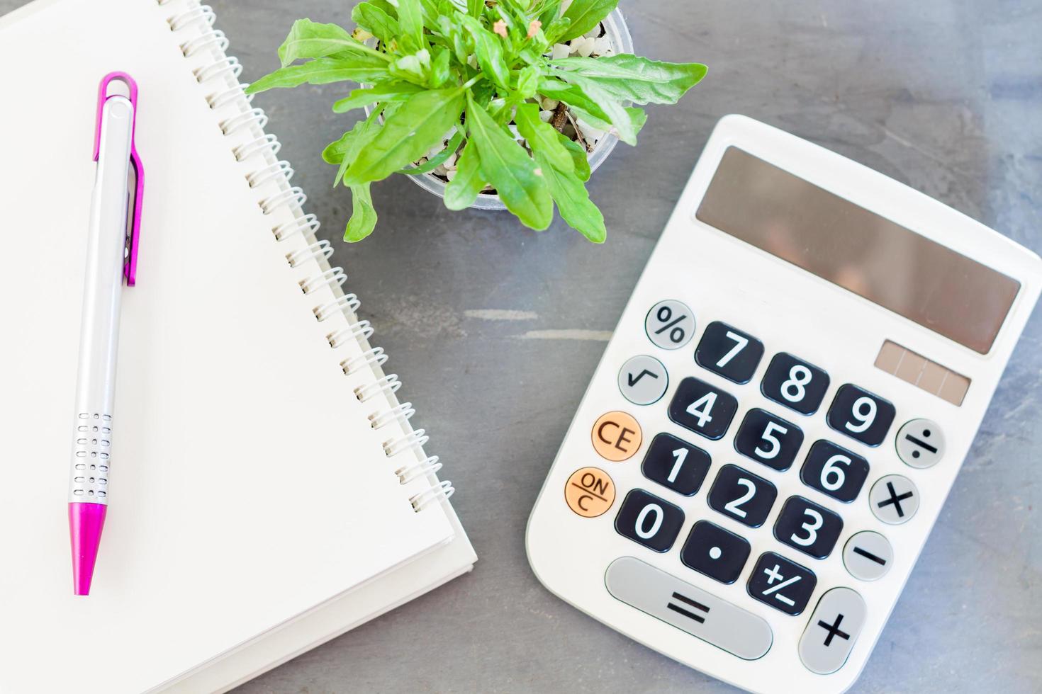 Notebook with a pen, calculator, and a plant photo