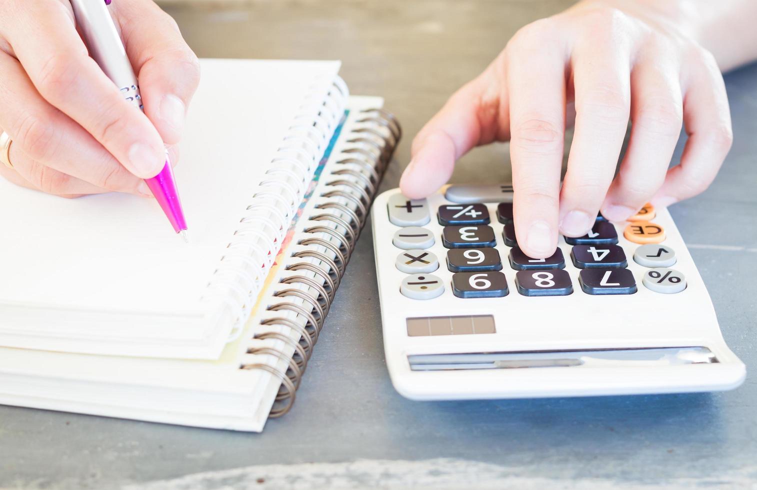 Close-up of a person using a calculator and writing in a notebook photo