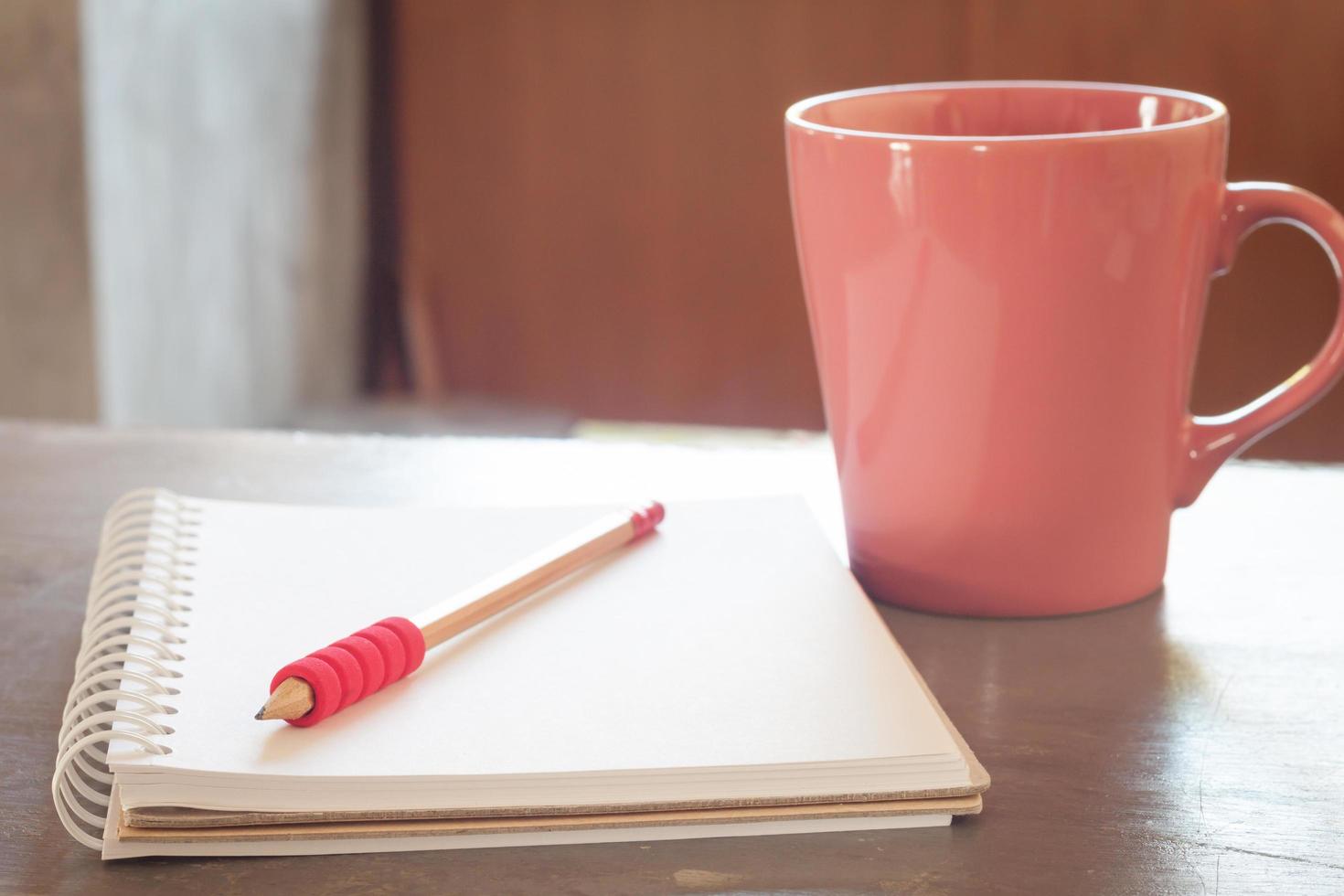 Pink coffee cup with a pencil and notebook photo