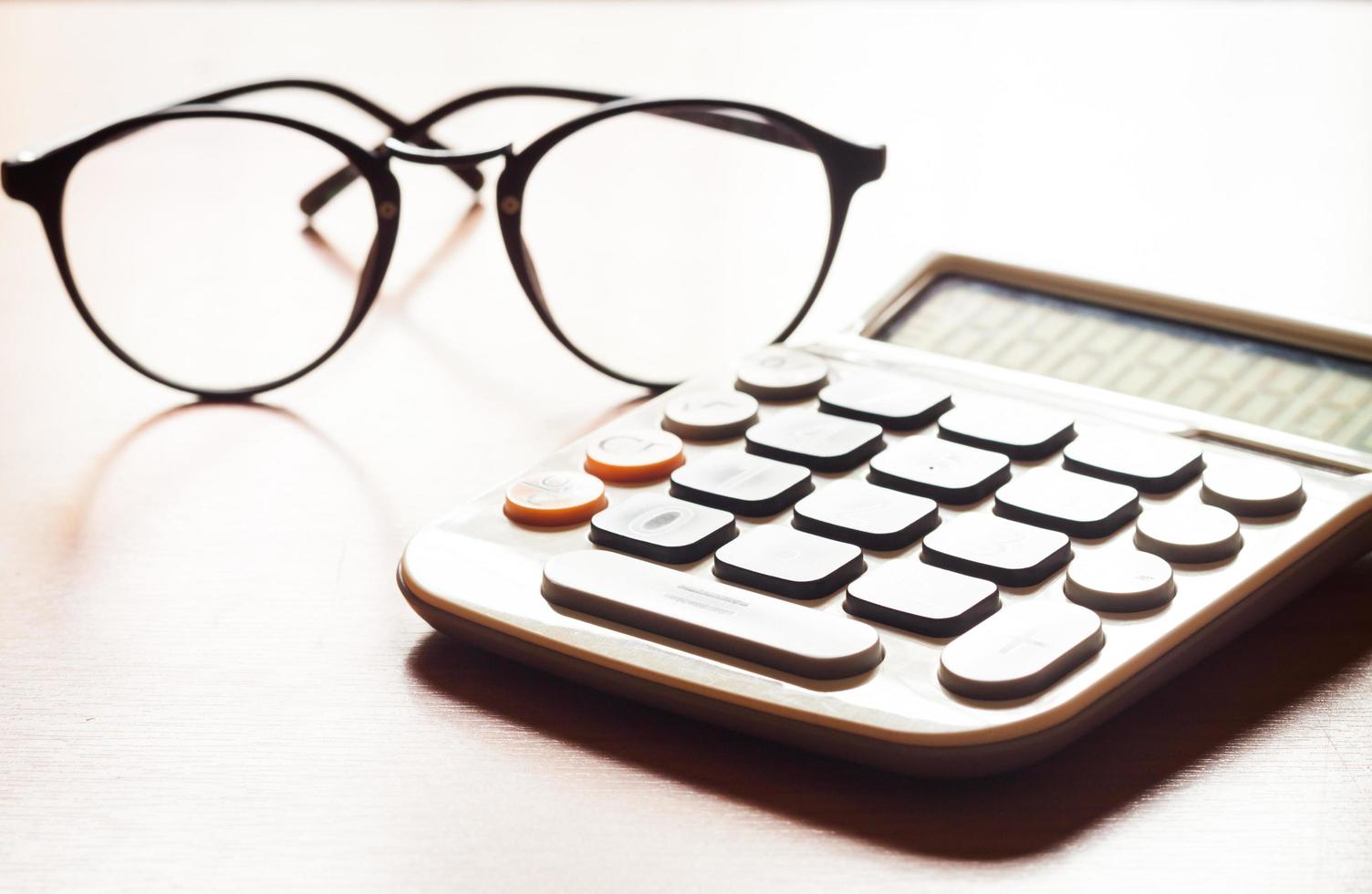 Calculator with a pair of glasses on a wooden table photo