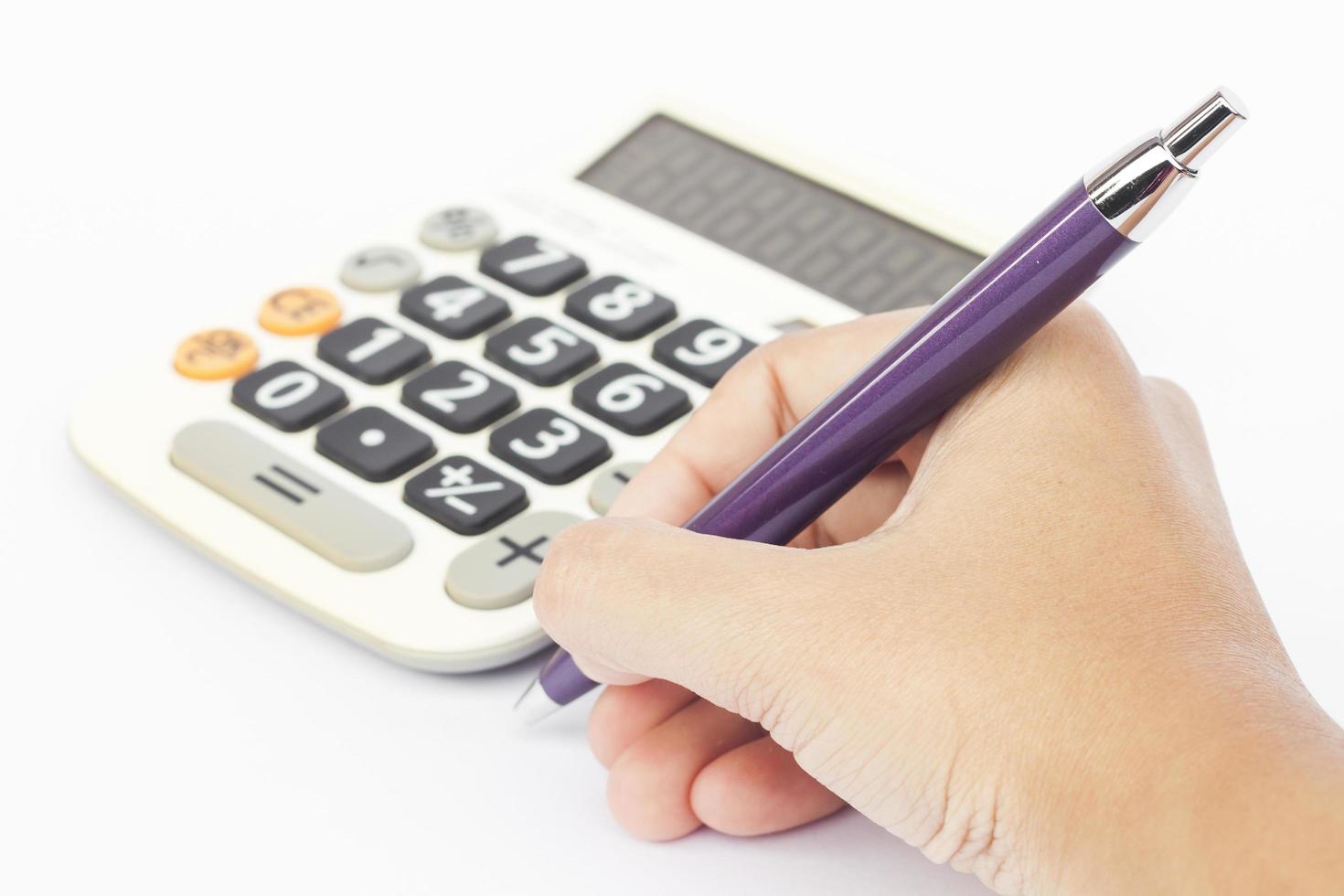 Calculator with hand holding a pen photo